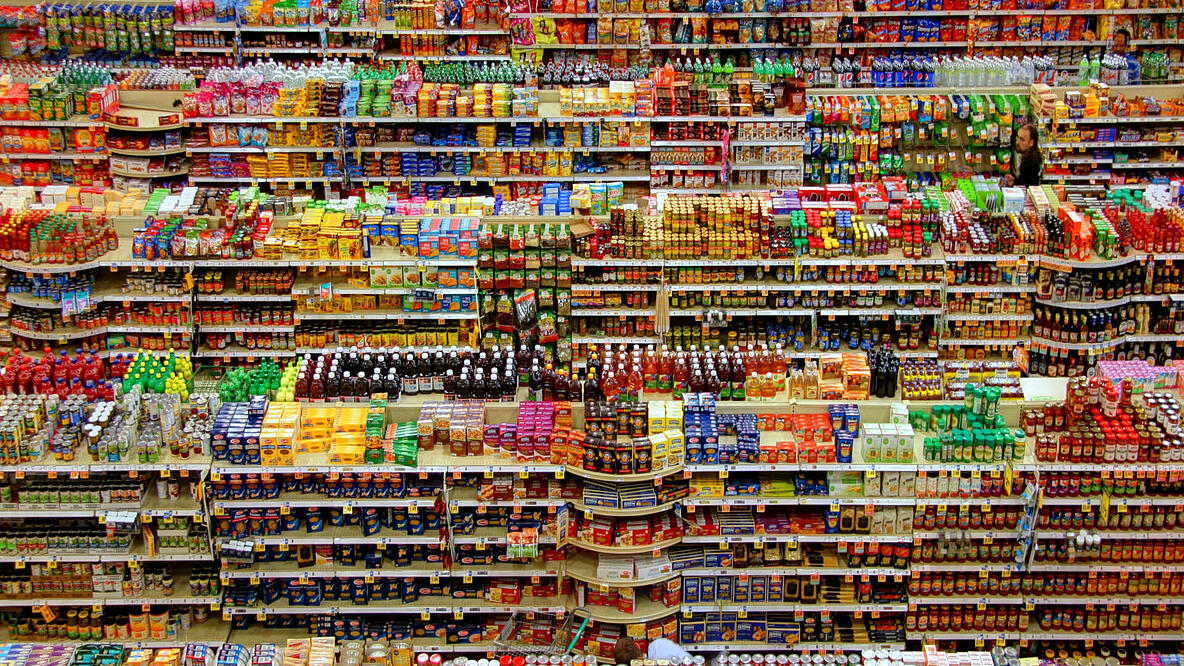 Regalreihen im Supermark, übervoll mit Lebensmittel in bunten Pakungen