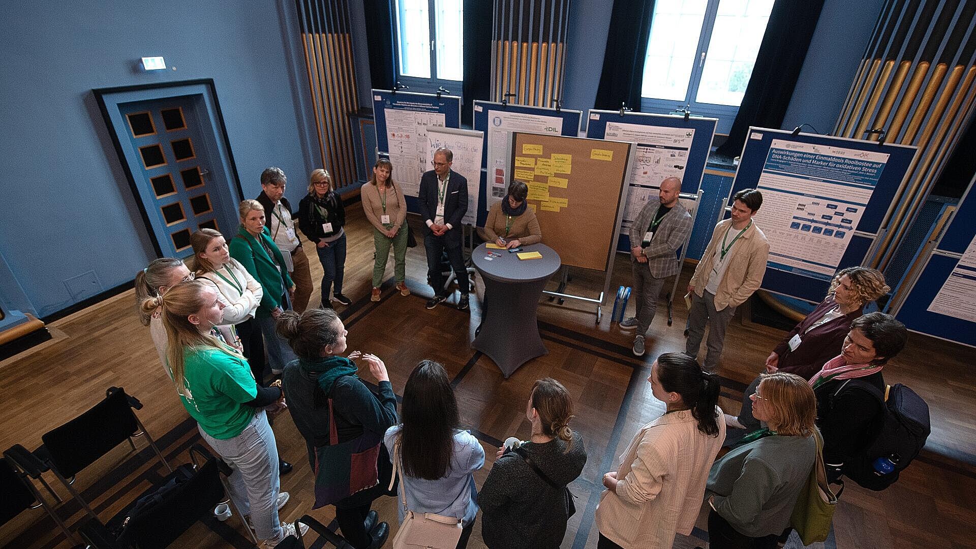 Mehrere Personen stehen beim Symposium um einen Stehtisch