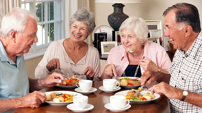 4 ältere Menschen sitzen am Tisch und essen gemeinsam
