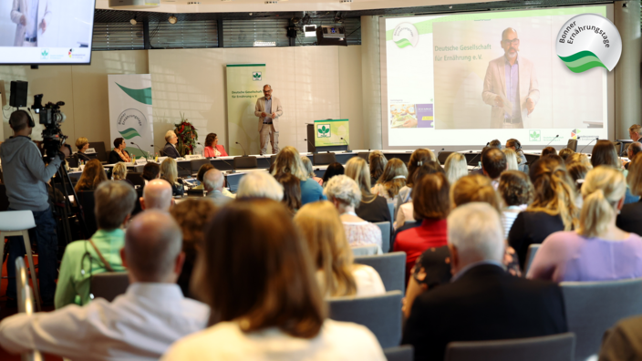 Plenum im Wissenschaftzentrum. Der Moderator redet zum Publikum.