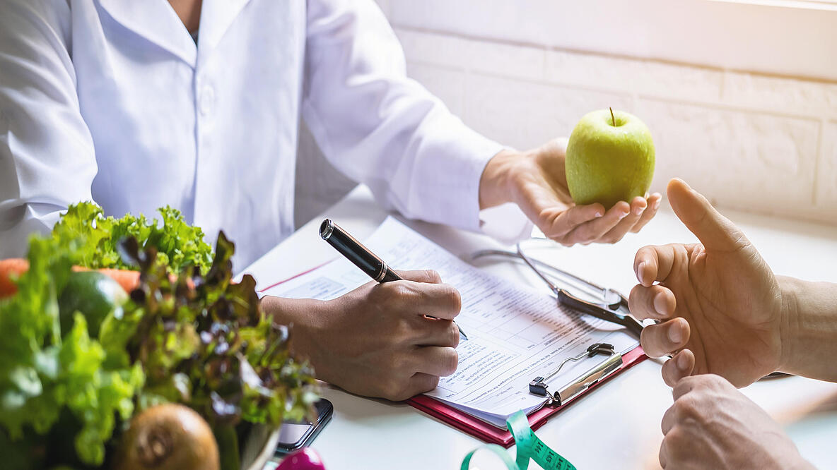 Ernährungsberaterin bei der Beratung eines Patienten mit Obst und Gemüse