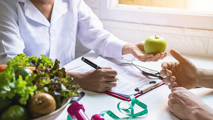 Ernährungsberaterin bei der Beratung eines Patienten mit Obst und Gemüse