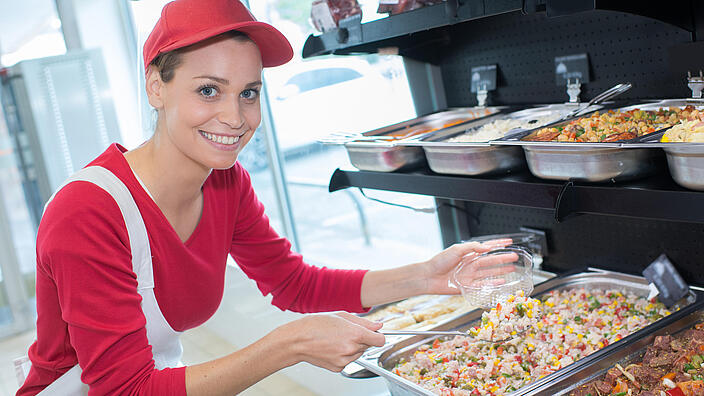 Frau lädt Essen auf einen Teller.