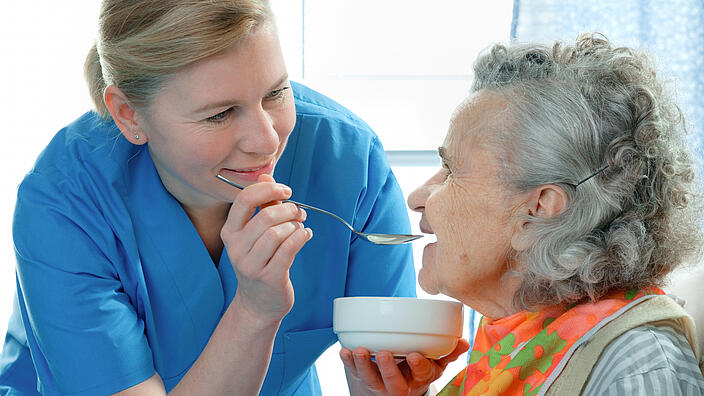Krankenschwester füttert Seniorin mit einem Löffel