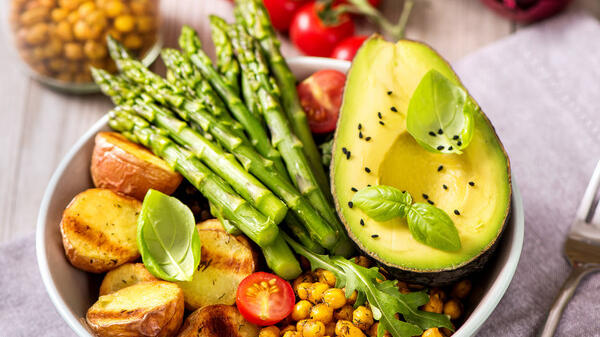 Bowl mit Spargel, Hülsenfrüchten, Kartoffeln,Avocado, Tomaten. Garnierung Basilikum