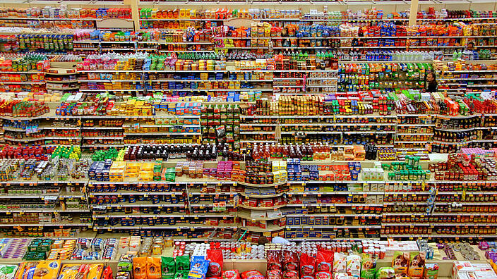 Regalreihen im Supermark, übervoll mit Lebensmittel in bunten Pakungen
