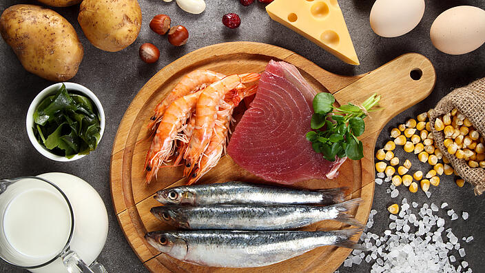 Jodhaltige Lebensmittel. Auf einem Brett befinden sich Krabben, Fische und ein Stück Thunfisch. 