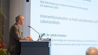 Herr Prof Linseisen steht am Pult und setlich sieht man die Präsentationsfolien.