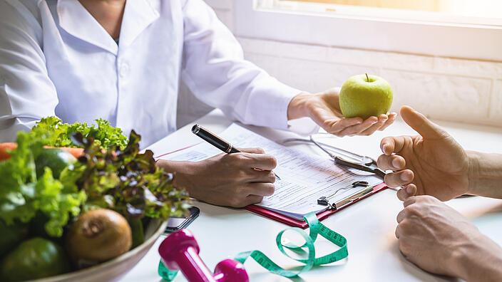 Ernährungsberaterin bei der Beratung eines Patienten mit Obst und Gemüse